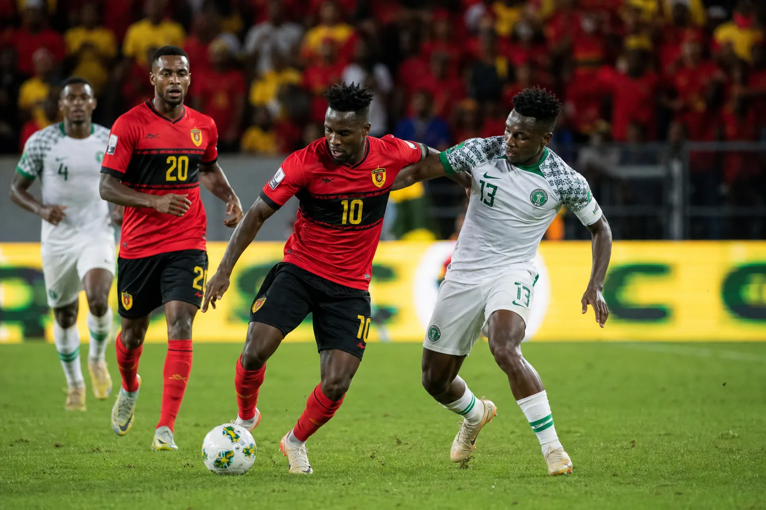 Fictional Angolan players in red and black competing in a tense World Cup group match