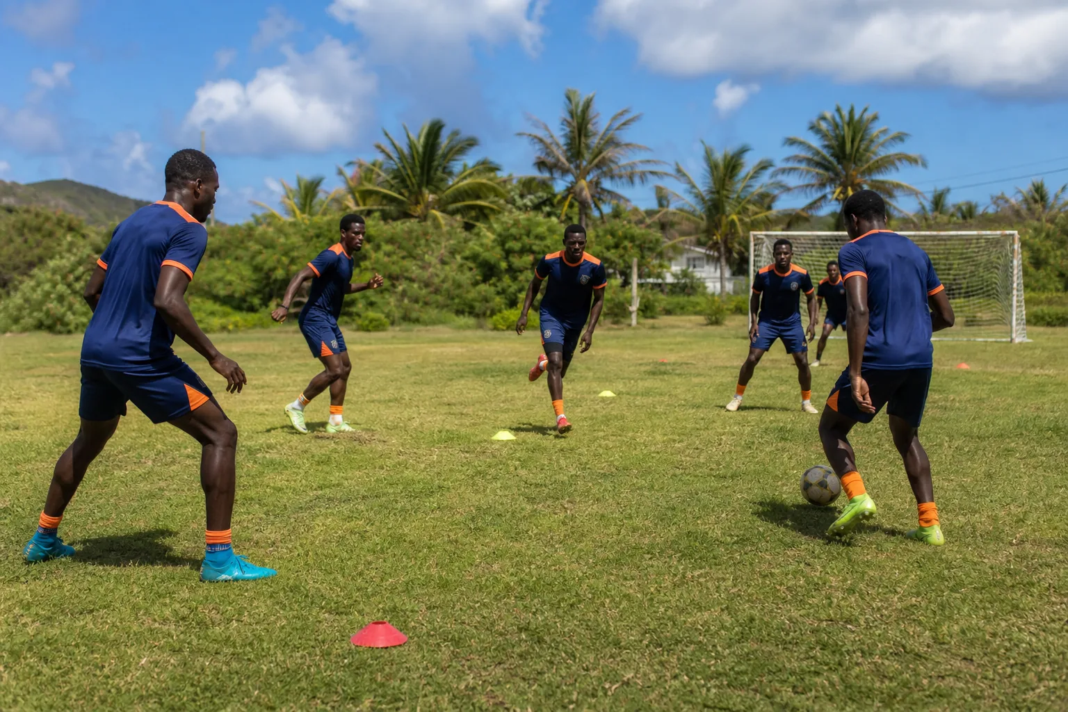 Anguilla national-team players training on a compact Caribbean football pitch with basic equipment