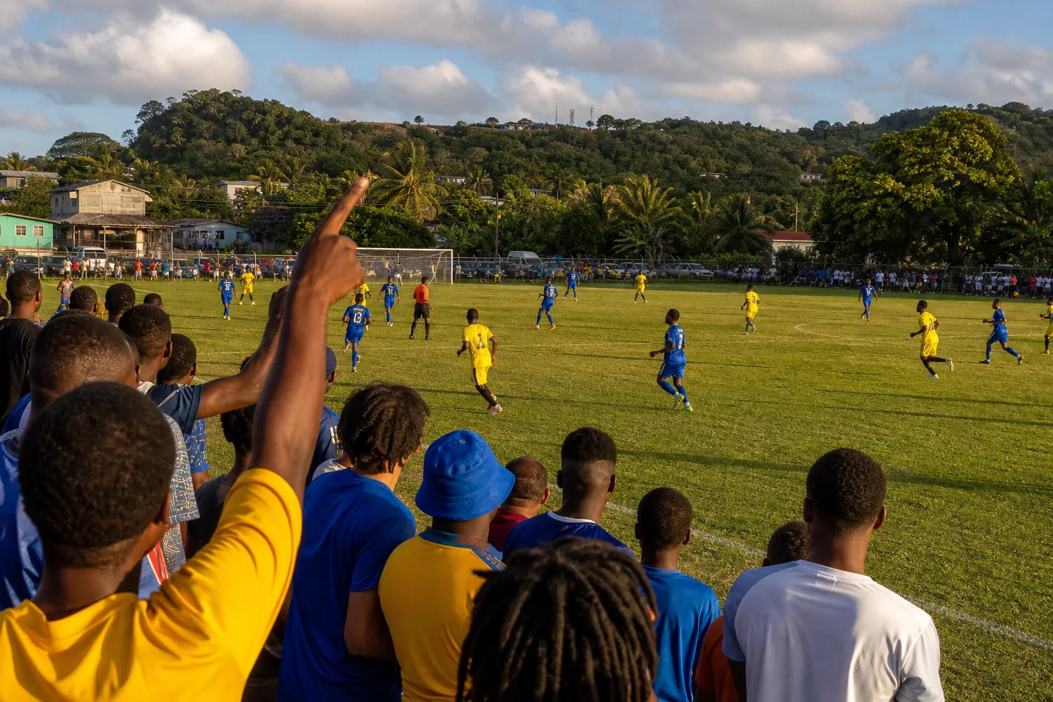 A community football match on a Barbados pitch with supporters and tropical island surroundings