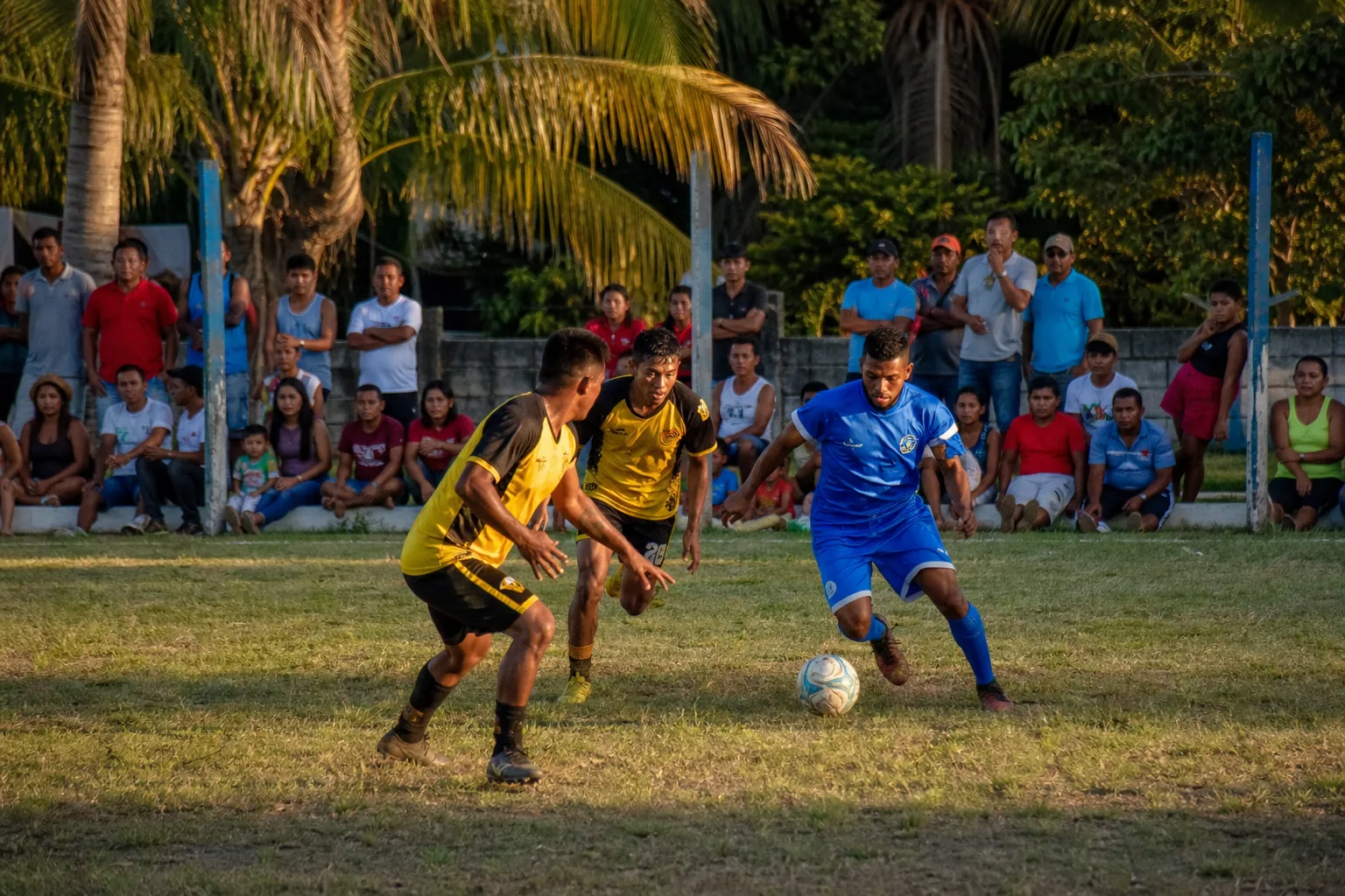 Belize national-team players training on a compact football ground with tropical surroundings
