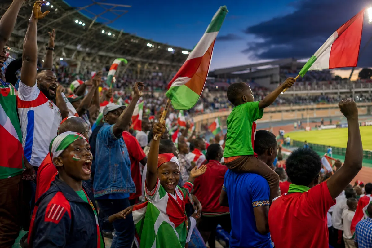 Burundian supporters celebrating in a packed stadium while waving red, white and green flags