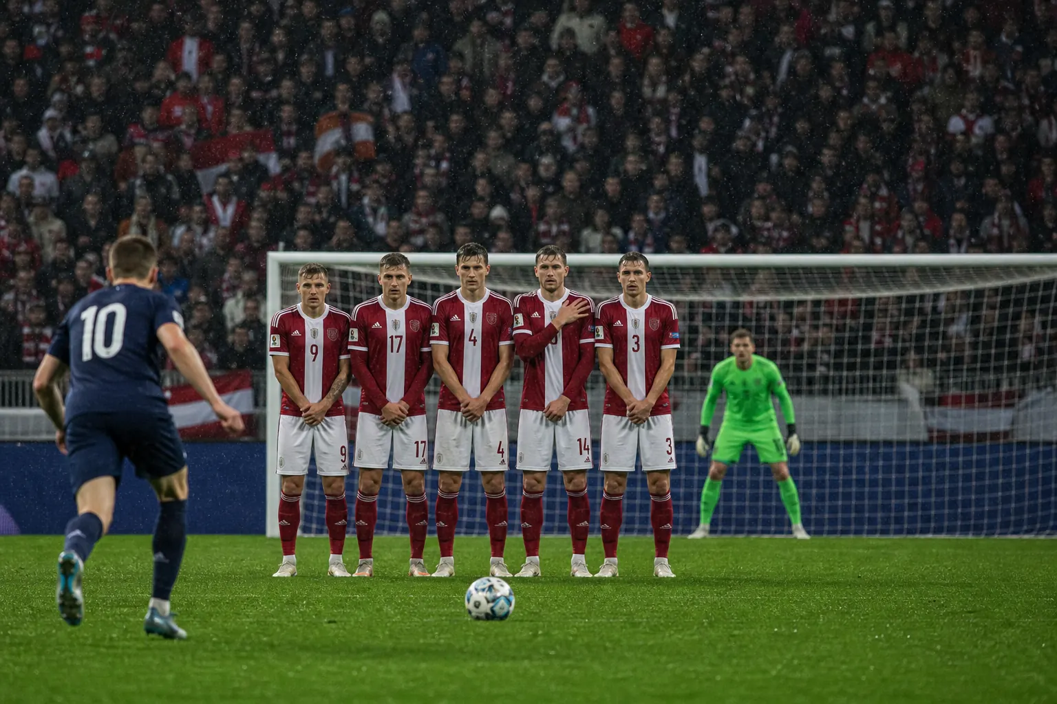Fictional Latvian footballers forming a disciplined defensive wall during a European qualifier