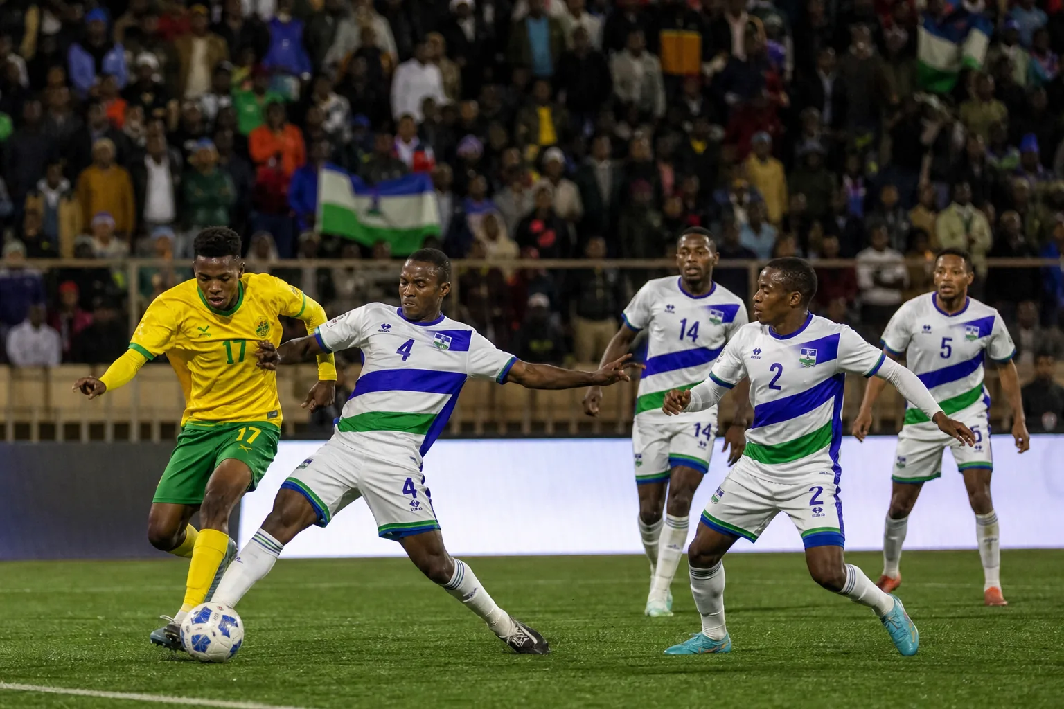 Lesotho footballers training on a high-altitude pitch surrounded by rugged mountains