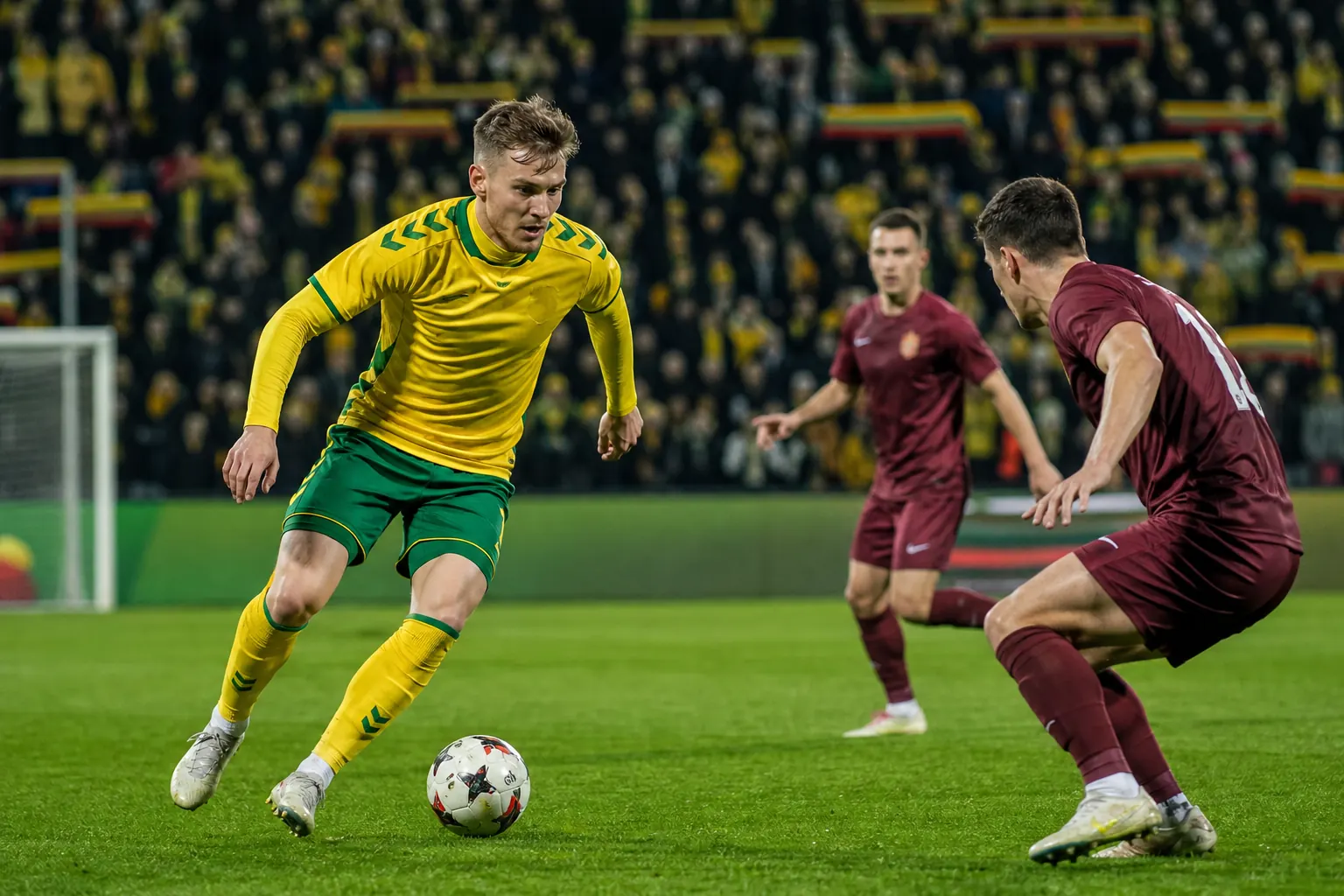 A fictional Lithuanian national-team star winger leading an attack in a packed international match