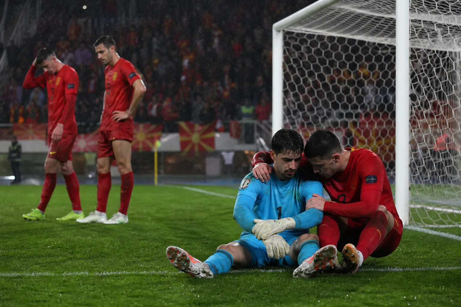 Fictional North Macedonian players reacting after a narrow qualifying setback