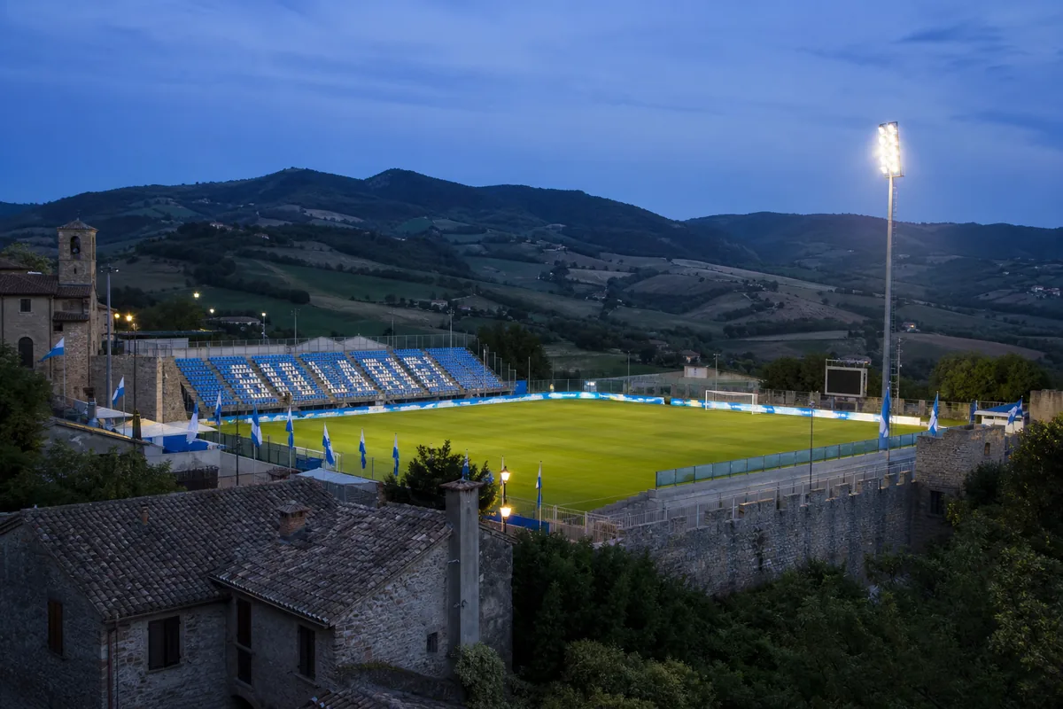 San Marino Stadium beneath evening lights with the surrounding hills and national colours