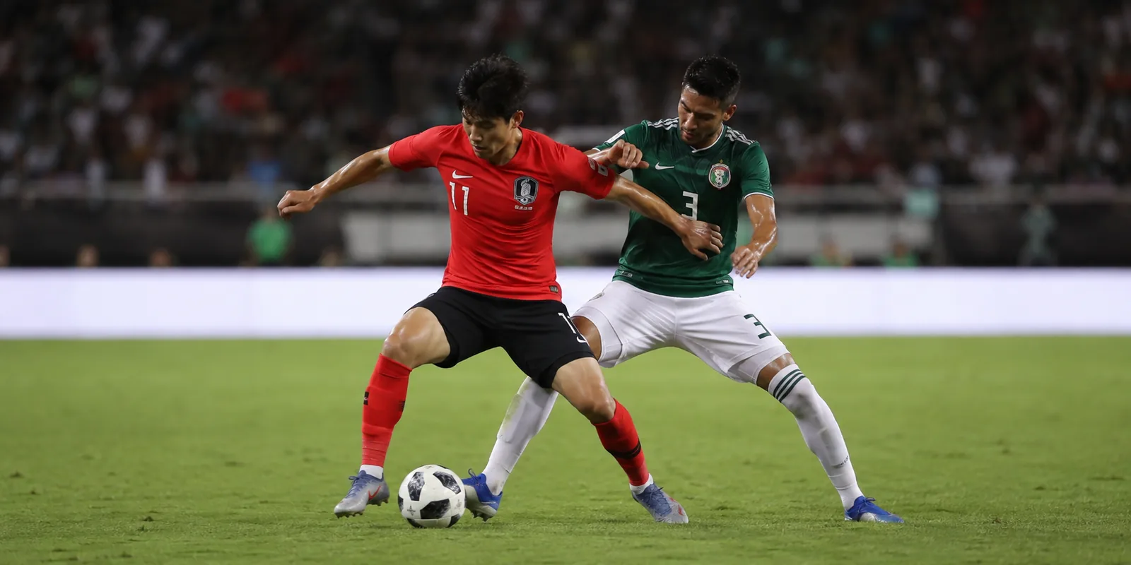 Fictional match-action illustration of a South Korean attacker shielding the ball from a Mexican defender